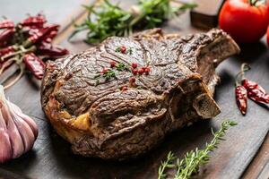 Grilled beef steak with spices herbs salt pepper and garlic on wooden cutting board photo