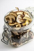 Dried mushrooms in a glass jar over white background photo