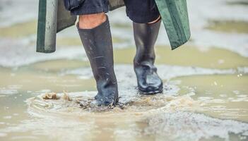 A man with black boots walks on a flooded road photo