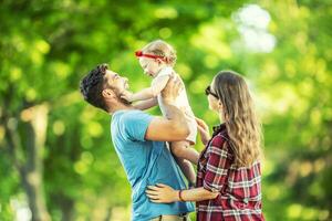 Happy family, father, mother and daughter are playing in the park and enjoying a sunny summer day photo