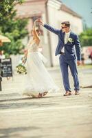 un novio bailando con su novia en el pueblo después un boda. todavía vistiendo hermosa batas y participación un ramo de flores hecho de blanco flores foto