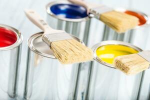 Close-up brushes lying on multicolored paint cans. photo