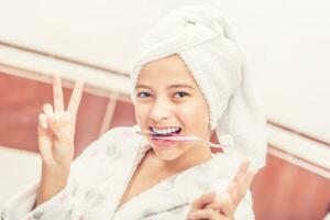 Adolescente niña en baño con cepillo de dientes. Mañana y noche dental higiene foto