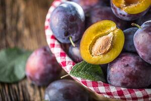 Plums. Fresh juicy plums in a bowl on a wooden or concrete board photo