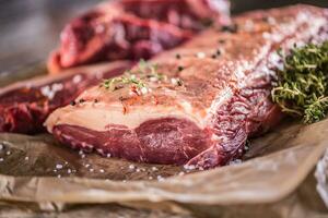 Raw rib eye beef steak with salt spices and herbs photo