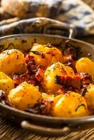 Potatoes. Roasted potatoes with bacon onion and sausages on old oak table photo