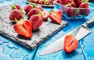 Fresh ripe strawberries washed with water on blue table photo