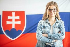Confident beautiful Slovak girl in glasses stands in front of the flag of her country photo