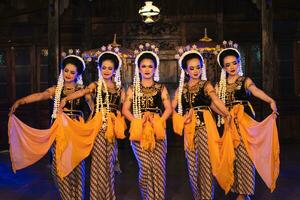 a group of Javanese dancers holding yellow shawls while dancing on stage photo