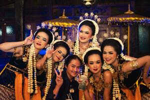 a group of Javanese dancers makes funny faces while taking pictures together on stage photo