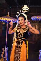 a Javanese dancer in jasmine and a yellow shawl takes selfies on stage after finishing dancing photo