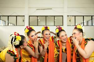 a group of traditional Javanese dancers laughing together with ridiculous faces and full of joy while on stage photo