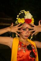 a Javanese dancer poses with sharp eyes and a golden costume on stage photo