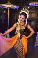 a Javanese dancer dances in a golden costume and a yellow shawl on stage photo