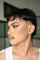 close up face of an Asian man with heavy makeup and dark eyebrows seen from the side photo