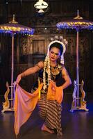 a Javanese dancer in jasmine and a yellow shawl takes selfies on stage after finishing dancing photo