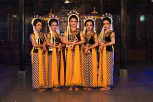 a group of Javanese dancers standing with their friends while wearing yellow costumes and shawls photo