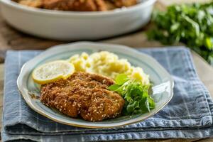 Schnitzel with sesame seeds served with potato mash and greens on a plate photo