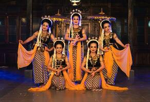 a group of Javanese dancers poses dancing with their friends while taking pictures on the stage photo