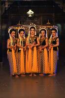 a group of Javanese dancers standing with their friends while wearing yellow costumes and shawls photo