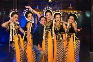 a group of Javanese dancers makes funny faces while taking pictures together on stage photo