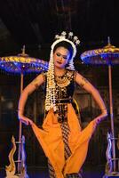 a Javanese dancer dances in a golden costume and a yellow shawl on stage photo