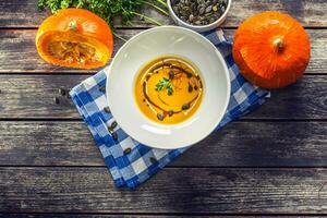 Pumpkin cream soup with seeds and parsley on kitchen table - Top of view photo