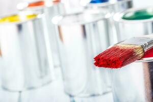 Close-up brush with red color lying on paint can. photo