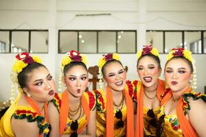 a group of traditional Javanese dancers laughing together with ridiculous faces and full of joy while on stage photo