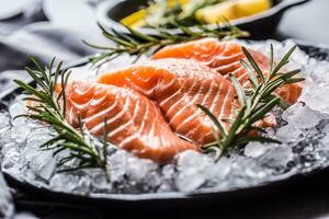 Portioned raw salmon fillets in ice on plate with lemon and rosemary photo
