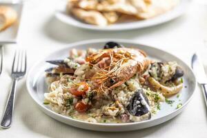 Risotto con frutti di mare served on a plate with nice decoration and table setting photo