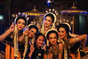 a group of Javanese dancers makes funny faces while taking pictures together on stage photo