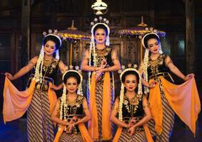 a group of Javanese dancers poses dancing with their friends while taking pictures on the stage photo