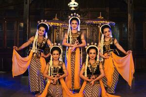 a group of Javanese dancers poses dancing with their friends while taking pictures on the stage photo