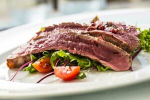 Close-up  juicy flank steak from vegetable salad. photo