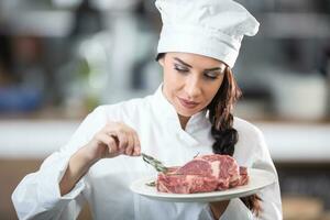 profesionalmente vestido cocinero cepillos crudo filete en un plato con primavera de Fresco Romero foto