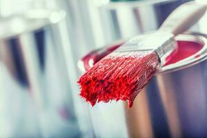 Close-up brush with red color lying on paint can. photo