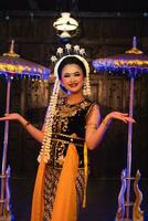a Javanese dancer in jasmine and a yellow shawl takes selfies on stage after finishing dancing photo