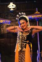 a Javanese dancer in jasmine and a yellow shawl takes selfies on stage after finishing dancing photo