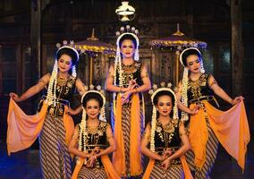 a group of Javanese dancers poses dancing with their friends while taking pictures on the stage photo