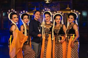 a group of Javanese dancers makes funny faces while taking pictures together on stage photo