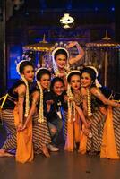 a group of Javanese dancers makes funny faces while taking pictures together on stage photo