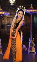 a Javanese dancer in jasmine and a yellow shawl takes selfies on stage after finishing dancing photo