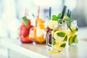 Various lemonades in mason jars with orange lime lemon otange strawberries and fresh fruit fruits photo