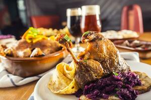 Roasted christmas duck leg red cabbage dumplings liver draft beer and baked buns photo