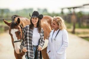 hembra caballo propietario consulta el veterinario acerca de el bienestar de sus animal en el rancho foto