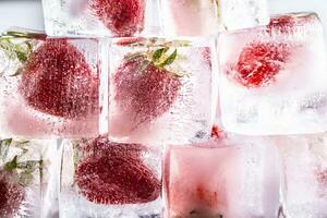 Fresh strawberries frozen in ice cubes - Close up. photo