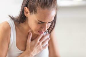 Woman heeling big pain on her chest, holding hand over her heart photo