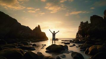 Happy man enjoying life on beach rocks by the ocean with arms wide open. silhouette concept photo