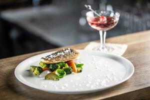 sano pescado cocido con al vapor vegetales servido en un plato siguiente a un negroni cóctel foto